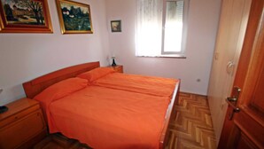 A bedroom with a wooden bed, a nightstand, a wooden wardrobe, and two framed paintings on the wall. - Apartment Branka for 2 -3 person (Premantura)