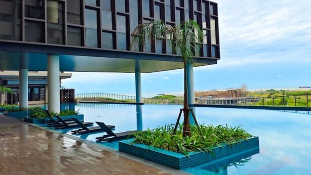 A modern building with a pool area, featuring lounge chairs and a view of the water. - Bali Service Residence•WiFi 500Mbps (Melaka)