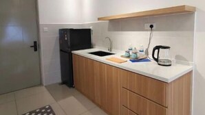 A modern kitchen with a white countertop, wooden cabinets, a black refrigerator, and a coffee maker. - Bali Service Residence•WiFi 500Mbps (Melaka)