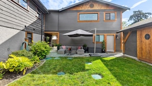 A two-story house with a covered patio area, a small garden, and a visible door.