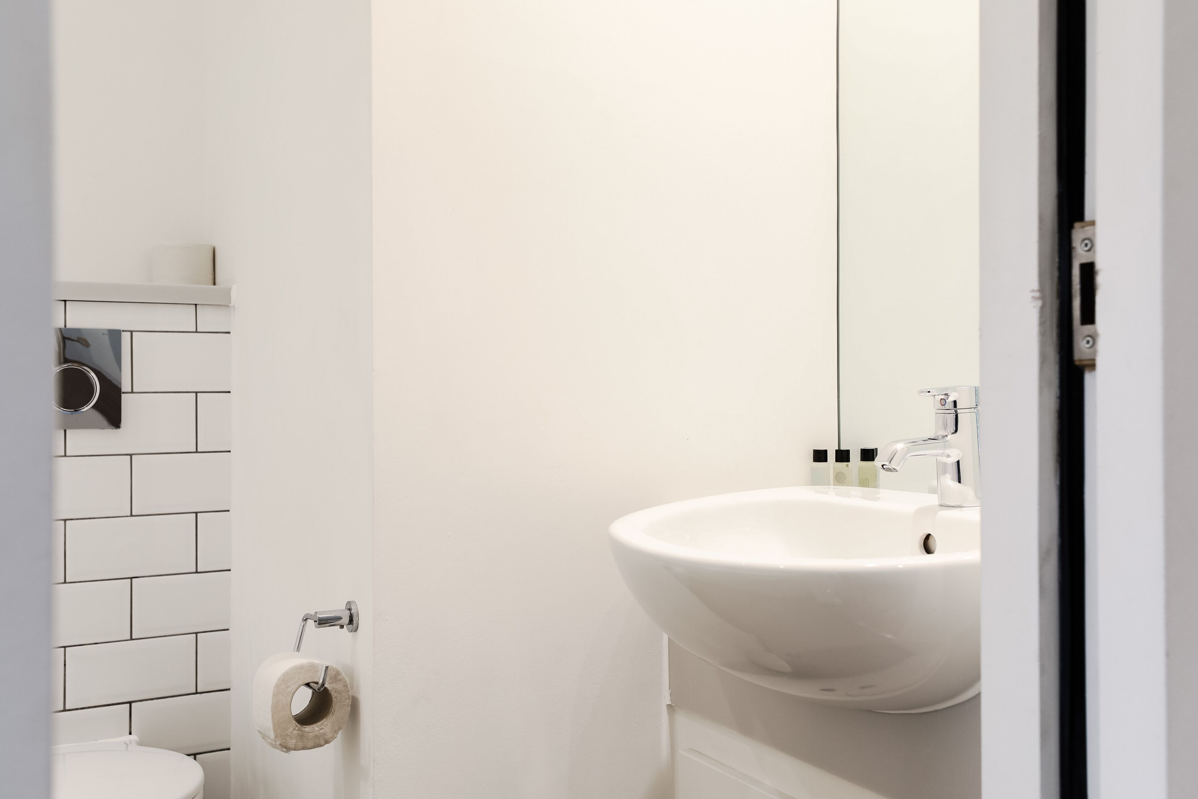 Een badkamer met een wit wastafel, toilet en toiletrolhouder aan de muur.