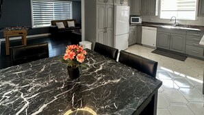 Una cucina moderna con mobili grigi, un tavolo da pranzo in marmo nero e una lampada a sospensione.