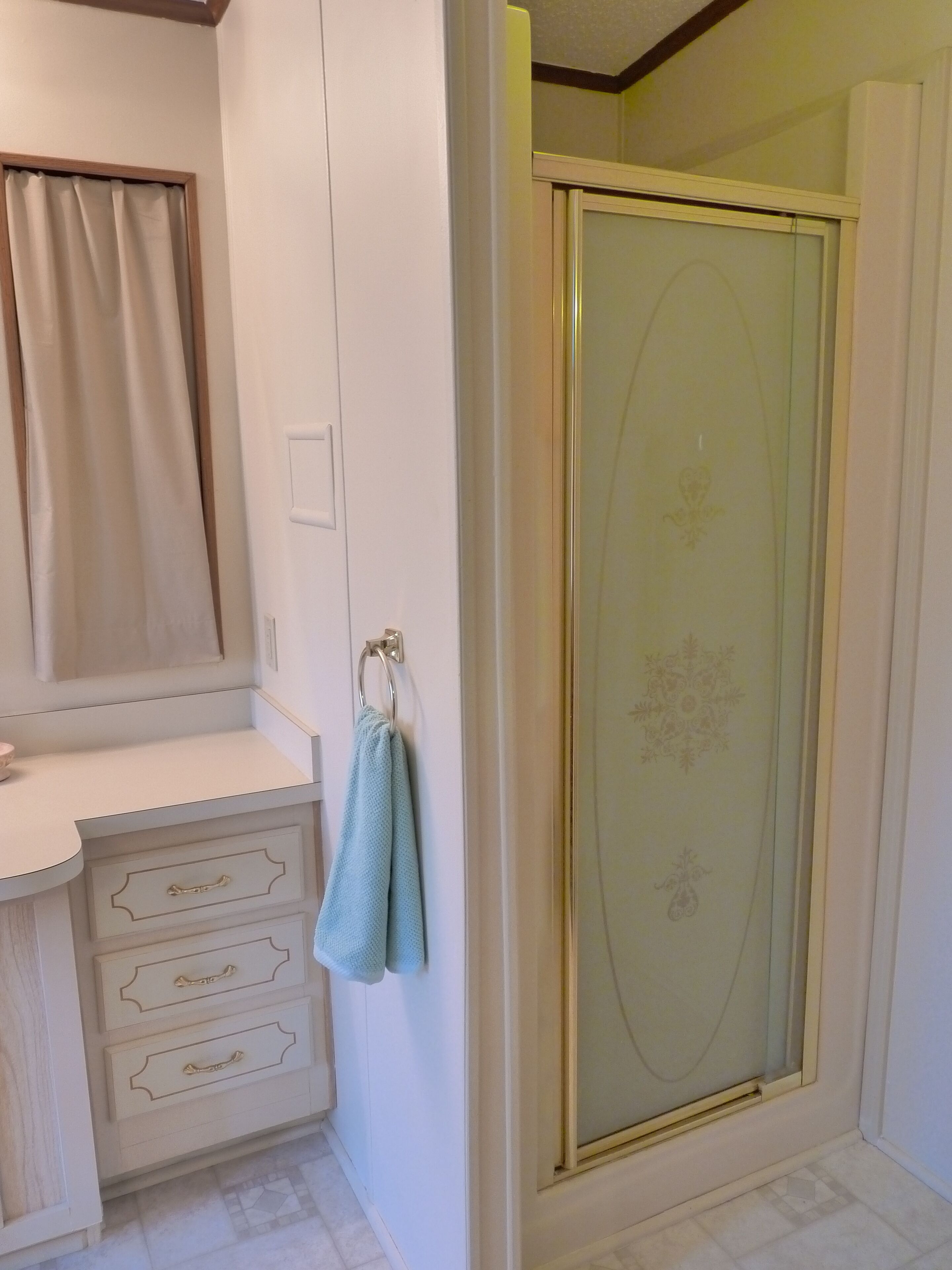 Un bagno con doccia, un mobile lavabo con cassetti e un asciugamano appeso a un gancio.