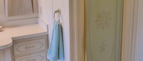 Un bagno con doccia, un mobile lavabo con cassetti e un asciugamano appeso a un gancio.