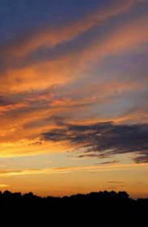 Un coucher de soleil avec la silhouette d’un paysage.