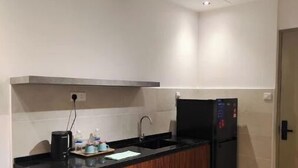 Eine kleine Küche mit schwarzer Arbeitsplatte, Holzschränken, einer Edelstahl-Spüle und einem schwarzen Kühlschrank.