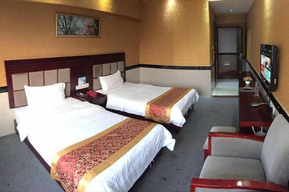 A hotel room with two beds, a TV, a desk, and a chair.
