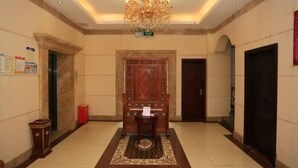 A lobby with a chandelier, a reception desk, a wooden door, and a red trash bin. - Mindu Hotel (Shenzhen)