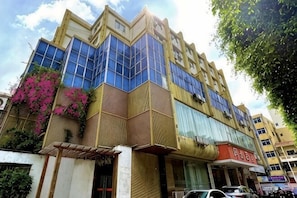 Un edificio de varios pisos con grandes ventanales, una entrada visible y un escaparate con señalización.