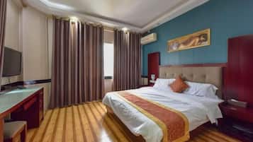 A hotel room with a bed, a desk, a TV, and a painting on the wall.