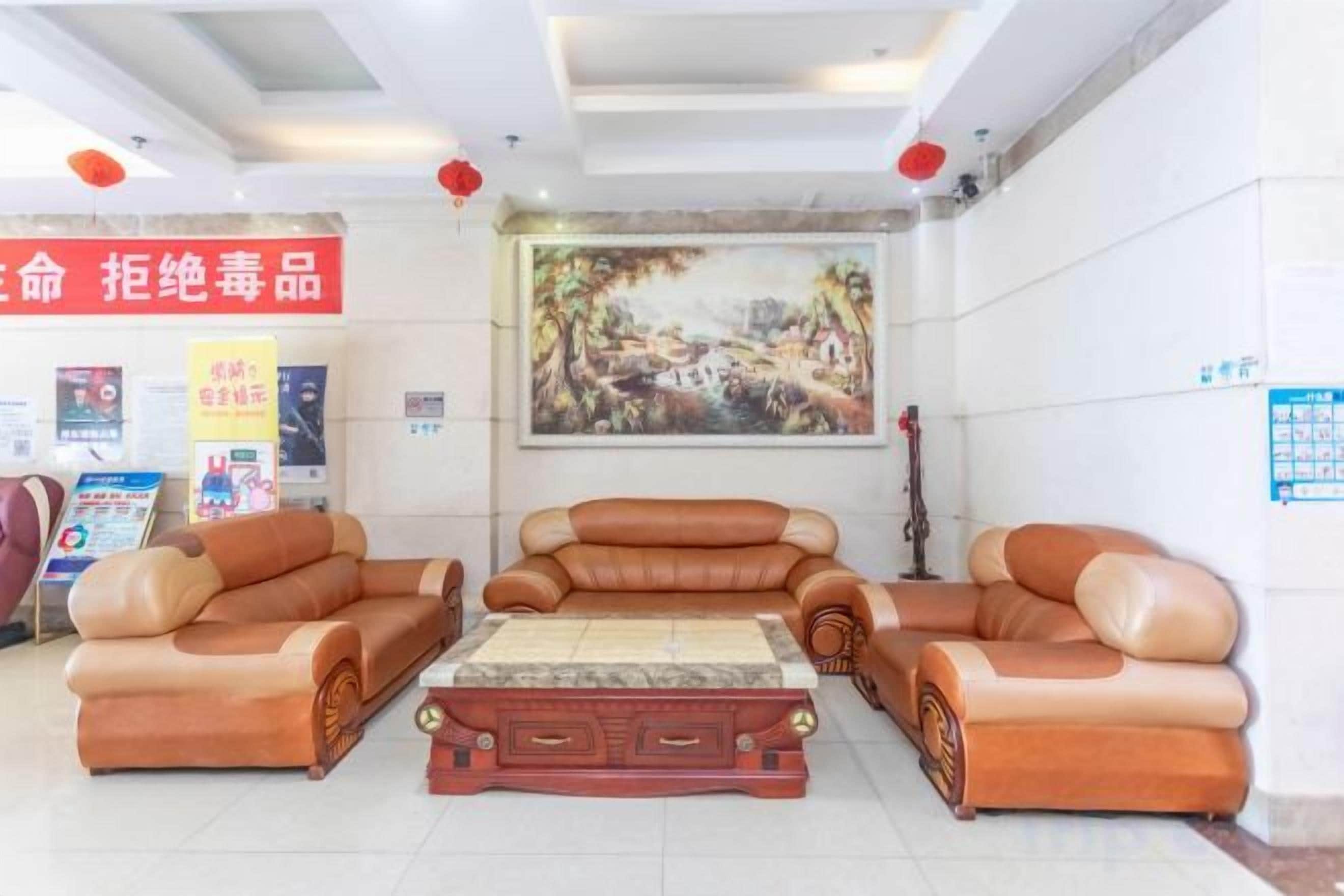 A lobby with leather sofas, a wooden coffee table, and a painting on the wall.
