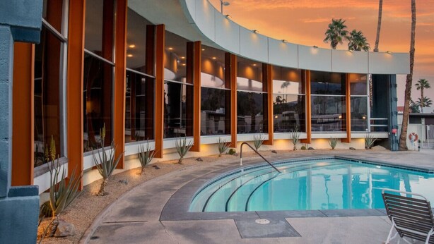 A modern building with a curved exterior, large windows, and a pool area. - Boho chic condo at the mid-century Ocotillo Lodge (Palm Springs)