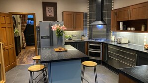 Una cocina moderna con una isla central, taburetes de bar, electrodomésticos de acero inoxidable y armarios de madera.