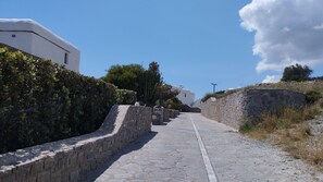 A stone pathway leading to a white building with a stone wall on one side.