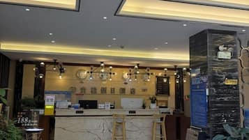 A hotel reception area with a marble counter, multiple light fixtures, and a signboard.