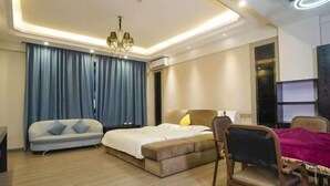A modern hotel room with a bed, a sofa, a chair, and a desk.