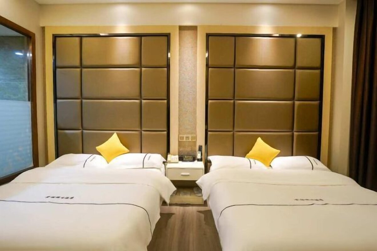 A hotel room with two beds, a nightstand, and a mirror.