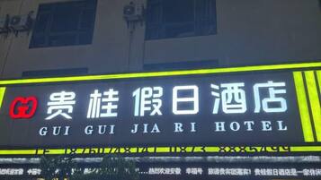 Un letrero de hotel con caracteres chinos y el nombre 'GUI GUI JIA RI HOTEL' en inglés.