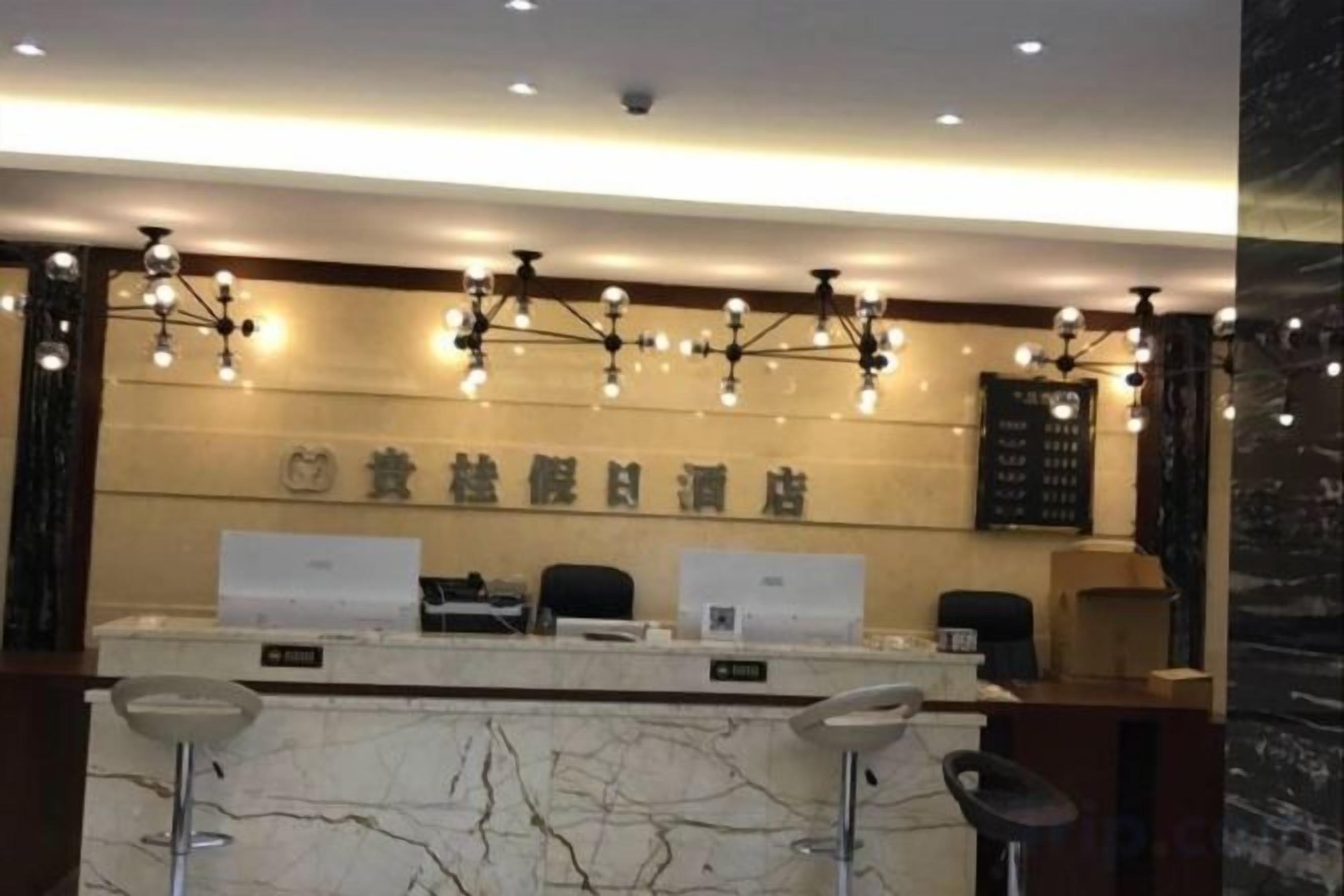A hotel reception area with a marble counter, two bar stools, and a reception desk.