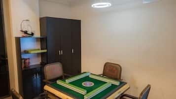 A room with a table set for a game, two chairs, a dark cabinet, and a ceiling light fixture.