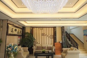 Amplia sala de estar con candelabro, sofás, una mesa de centro y una escalera.