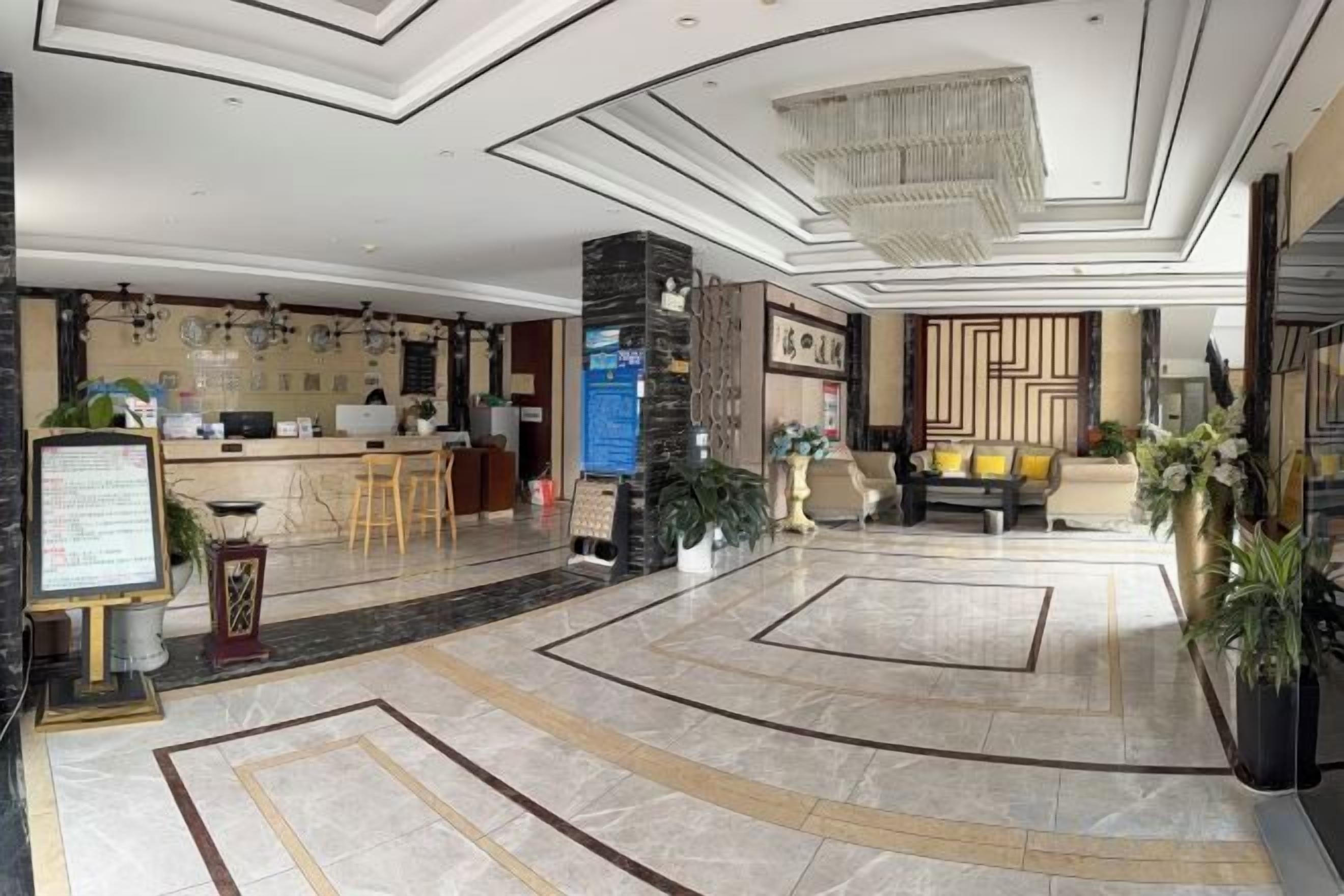 A hotel lobby with a reception desk, seating area, and a decorative wall.