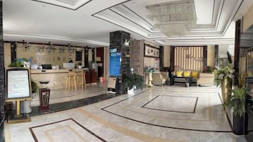 A hotel lobby with a reception desk, seating area, and a decorative wall.