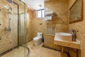 A bathroom with a glass-enclosed shower, a toilet, and a sink with a mirror.