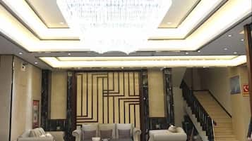 A hotel lobby with a chandelier, sofas, a coffee table, and a staircase.