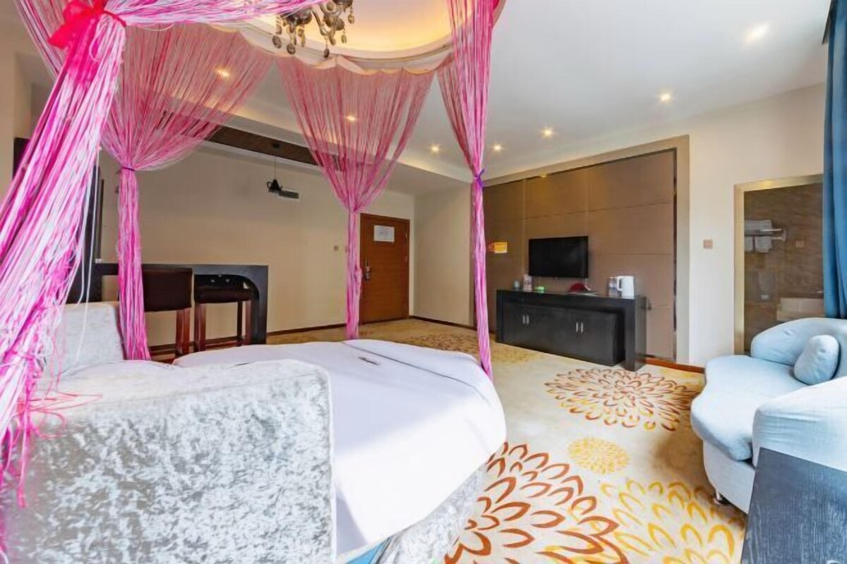 A hotel room with a bed, a sofa, a television, and a desk.