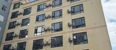 Un edificio de hotel de varios pisos con unidades de aire acondicionado en la fachada.