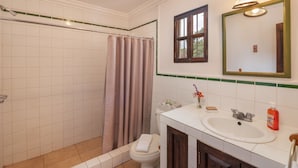 A bathroom with a shower, toilet, sink, and mirror. - Casita El Mirador  (Antigua Guatemala)