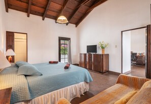 Relax in this serene bedroom with a large bed, wooden bench, and flat-screen TV.