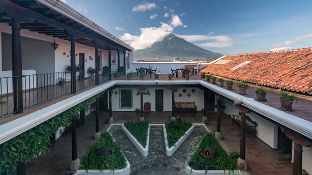 A courtyard with a central garden, a covered seating area, and a view of a mountain. - Casita El Mirador  (Antigua Guatemala)