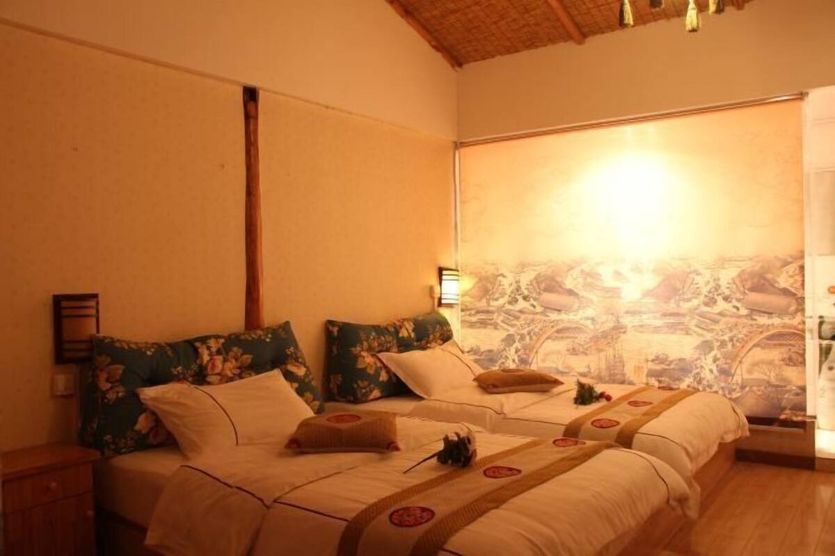 A room with two beds, a wooden ceiling, and a mural on the wall.