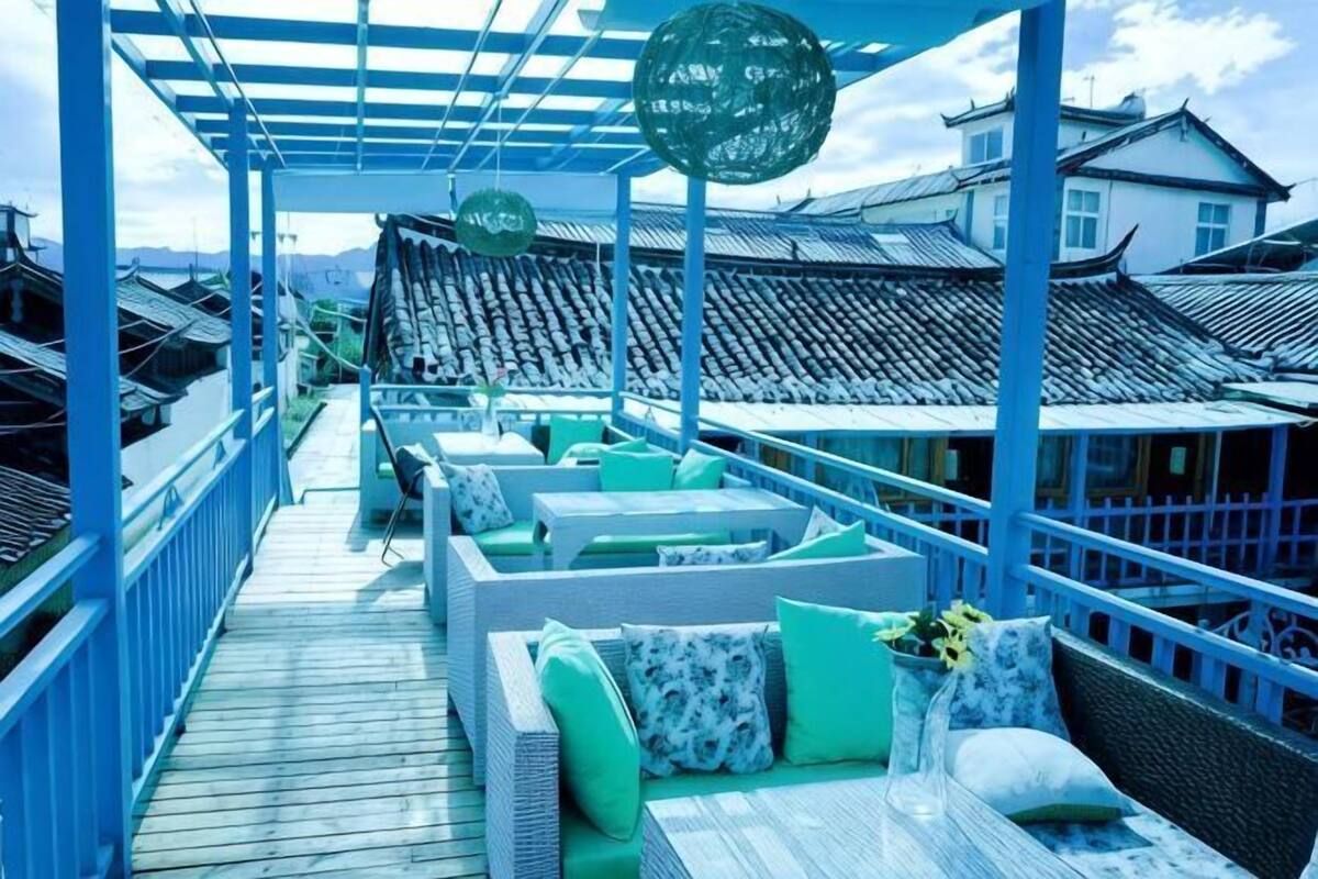 A covered outdoor seating area with wicker furniture and a view of traditional buildings.