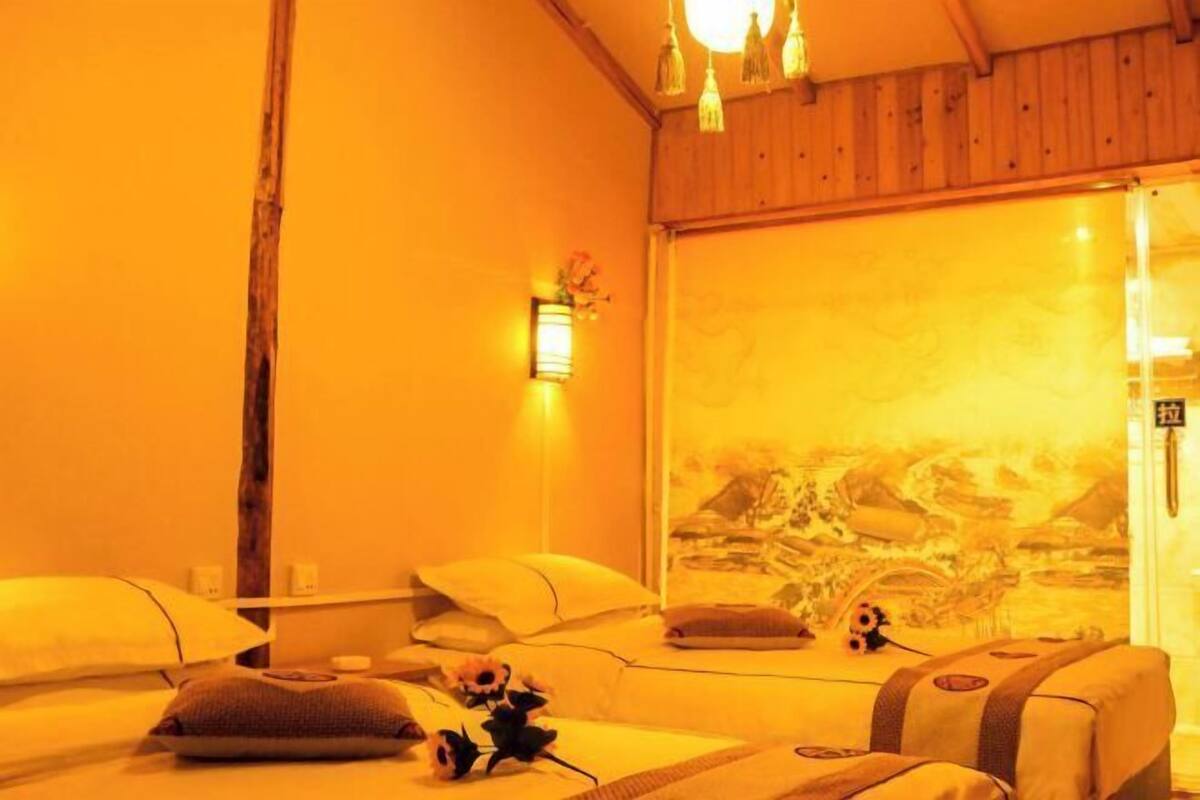A room with a bed, pillows, a wall-mounted light, and a window with a view.