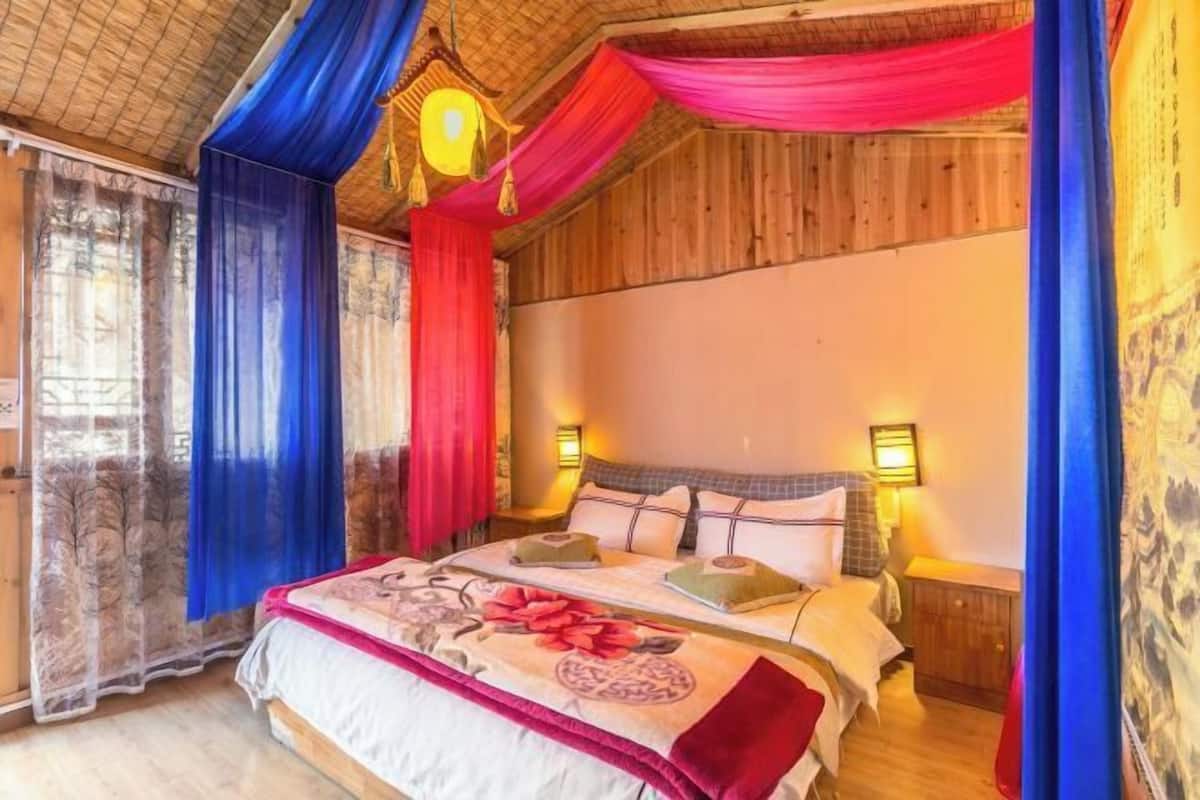 A bedroom with a large bed, two bedside tables, and a wooden ceiling.