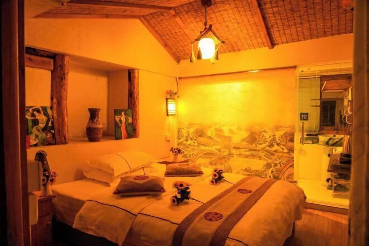 A room with a bed, a mirror, a wall with a mural, and a hanging light fixture.