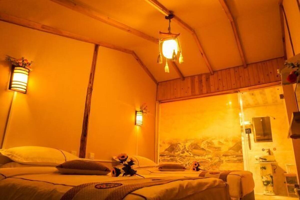 A cozy room with a bed, two wall-mounted lamps, and a wooden ceiling.