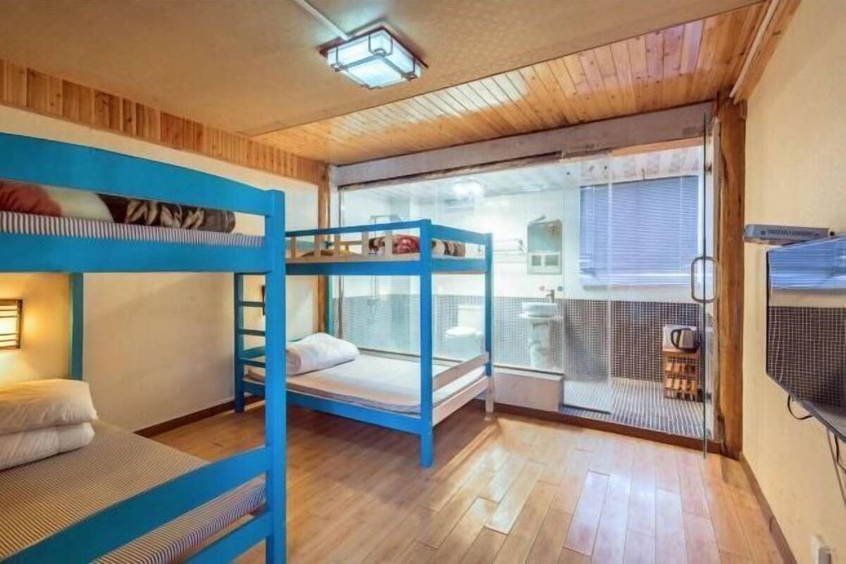 A room with bunk beds, a small window, and a kitchenette.