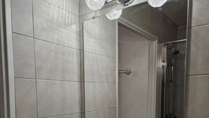 A bathroom with a white sink, a mirror, and a shower.