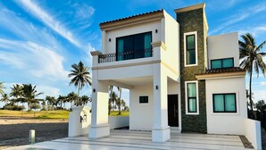 Una casa moderna de dos pisos con balcón, ventanas amplias y fachada de piedra.