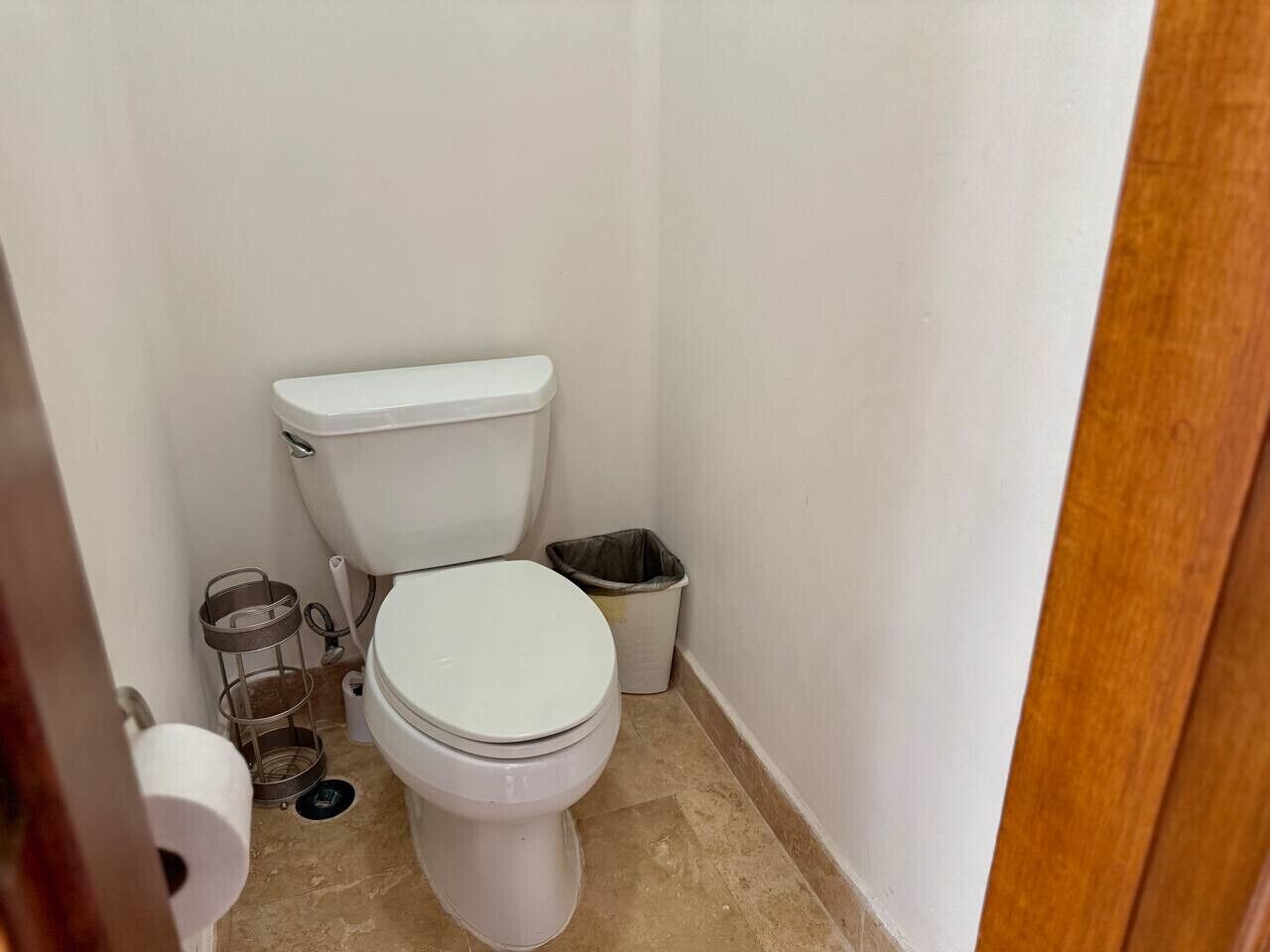 A small, clean bathroom with a white toilet, a trash bin, and a metal waste basket.
