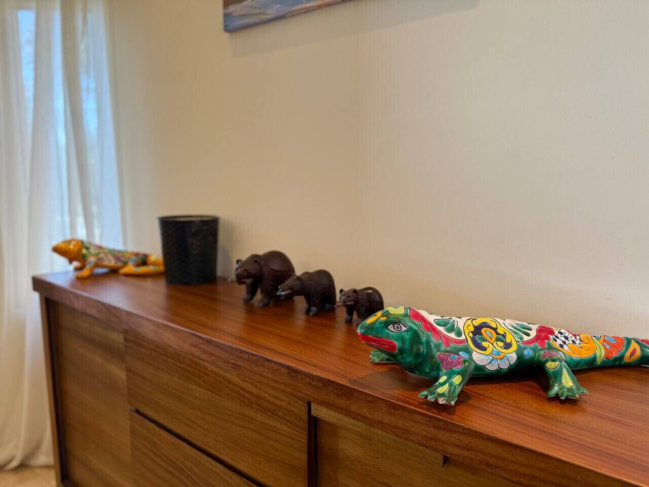 Un bureau en bois orné d’une figurine de lézard peinte aux couleurs vives, d’une tasse noire et de petites figurines d’animaux.