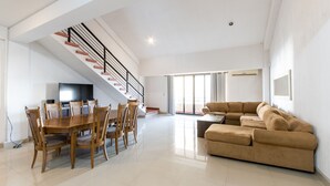 A spacious living area with a dining table, chairs, a sofa, and a staircase. - Marina del Rey (Mazatlán)