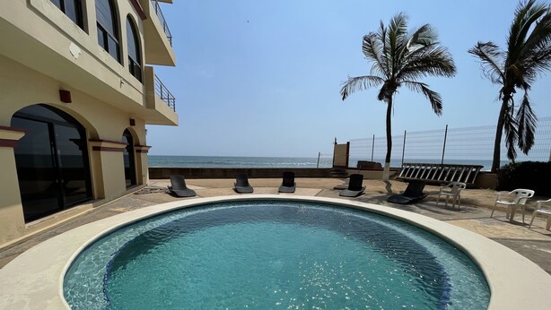 A swimming pool with lounge chairs, a view of the ocean, and palm trees. - Marina del Rey (Mazatlán)