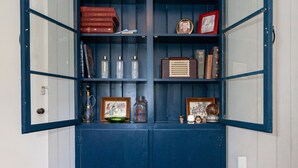 Een blauwe kast met glazen deuren, gevuld met boeken, een wereldbol en decoratieve objecten.
