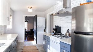 Een moderne keuken met witte kasten, een roestvrijstalen koelkast, een gasfornuis en een ingebouwde oven.