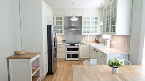 Een moderne keuken met witte kastjes, roestvrijstalen apparatuur en een houten eettafel.